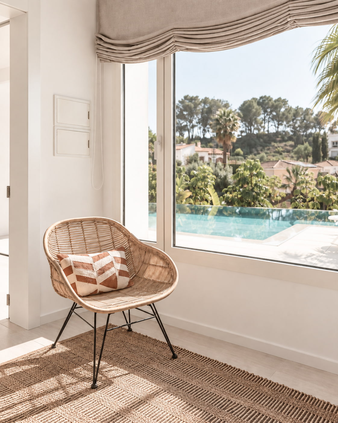 Butaca junto a un ventanal con vistas a la piscina, en una villa reformada por Arauz Tecnics
